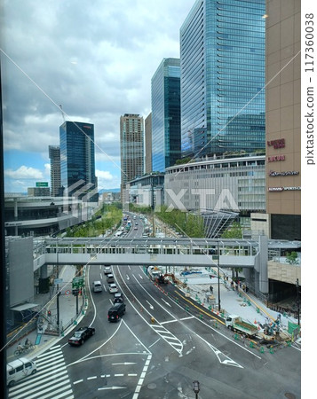 多雲天空下建築物和行道樹前正在施工的道路 117360038