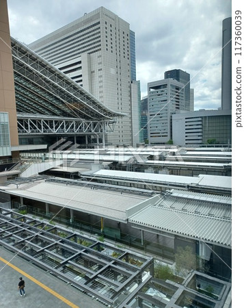 在陰雲密布、城市景觀寒冷灰暗的環境中,一位行人走在黃色的觸覺鋪路磚旁,背景是車站大樓光滑的屋頂 在陰雲密布、城市景觀寒冷灰暗的環境中,一位行人走在黃色的觸覺鋪路磚旁,背景是車站大樓光滑的屋頂 117360039