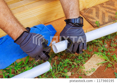 Plumber installed glues plastic PVC pipes for laying water line 117360195