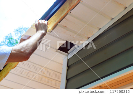 Plastic soffit boards are mounted to roof rafters of house ceiling 117360215
