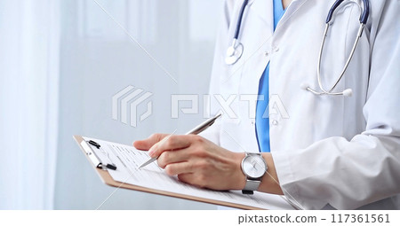Female doctor taking notes on clipboard. Close-up of a unrecognizable female professional writing and filling up medication history records form 117361561
