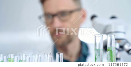Man researcher with safety glasses is working with lab tubes using a pipette in laboratory, close-up of lab equipment. Science and medicine 117361572