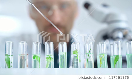 Man researcher with safety glasses is working with lab tubes using a pipette in laboratory, close-up of lab equipment. Science and medicine 117361576