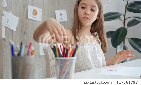Young girl choosing colored pencils and picking a pencil from a colorful set for a creative activity Young girl choosing colored pencils and picking a pencil from a colorful set for a creative activity 117361788