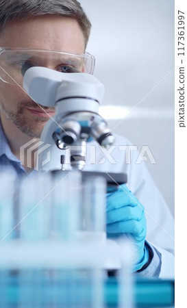 Man scientist with protective glasses and gloves is using micros Man scientist with protective glasses and gloves is using micros 117361997