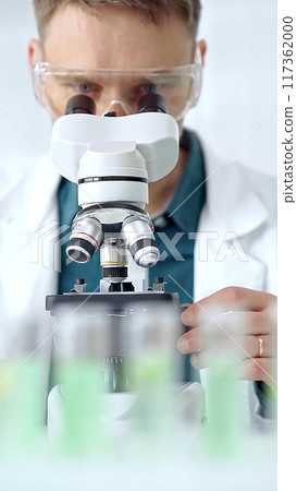 Man scientist with protective glasses using microscope in laboratory. Microbiology science concept Man scientist with protective glasses using microscope in laboratory. Microbiology science concept 117362000