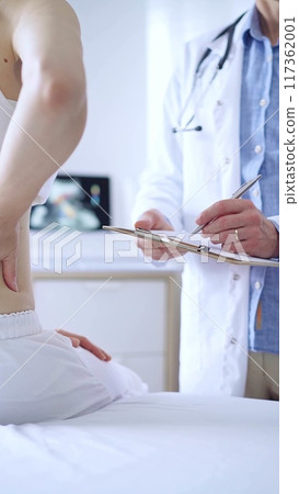 Doctor and patient. Physician is making notes on a clipboard while patient woman is describing something. Pediatrician, medicine concept 117362001
