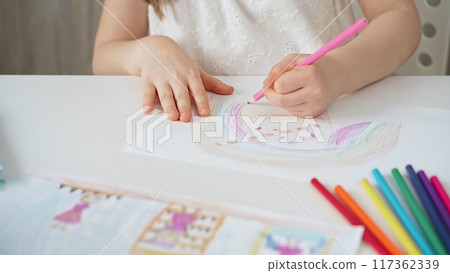 Close-up of a child's hands coloring a drawing with bright pencils. Young girl engaging in colorful artistic drawing and coloring activity using pencils. Enhancing creativity. Imagination 117362339