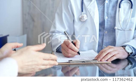 Doctor and patient conversation with clipboard in clinic office. Physician is making notes while listening woman. Medicine and Health care Doctor and patient conversation with clipboard in clinic office. Physician is making notes while listening woman. Medicine and Health care 117362462