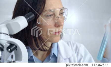 Female scientist analyzing sample of a test tub in laboratory setting. Science concept 117362486