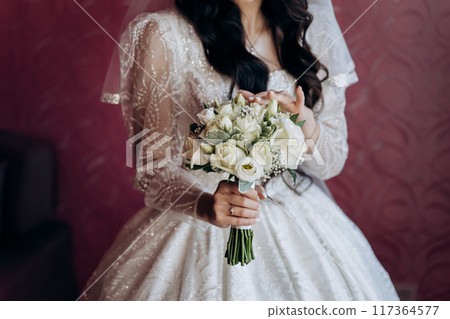 Elegant bride holding a delicate white rose bouquet, perfect for capturing timeless wedding moments 117364577