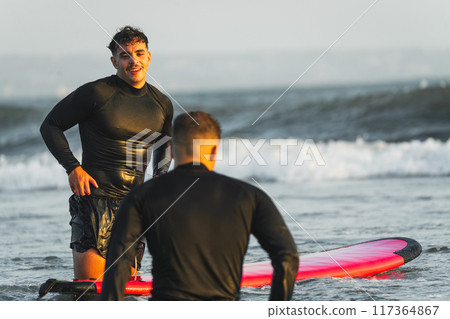 Friends surfing on the beaches of Bali during their vacation Friends surfing on the beaches of Bali during their vacation 117364867