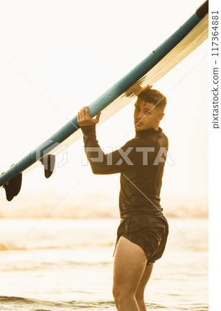 Surfer watching with his surfboard during sunset at the beach Surfer watching with his surfboard during sunset at the beach 117364881