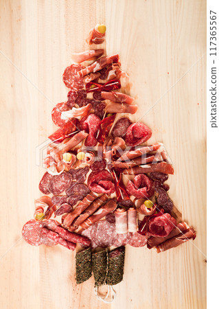 Christmas tree made of sausage on a background of a wooden wall Christmas tree made of sausage on a background of a wooden wall 117365567