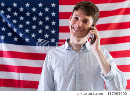 Satisfied student talking on mobile phone against background of USA flag 117365600