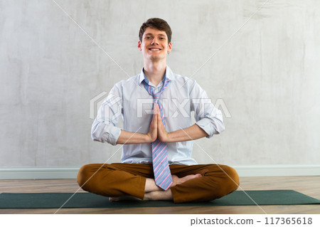 Young businessman doing yoga in office 117365618