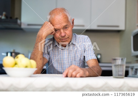 Thoughtful man sitting at table 117365619