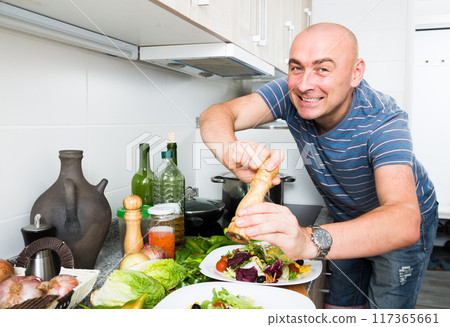 Ordinary man sprinkle with pepper salad 117365661