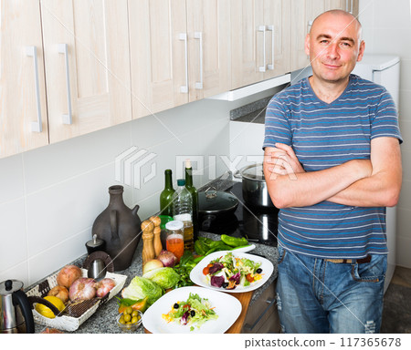 Man in the prime of life in kitchen prepared two salads 117365678