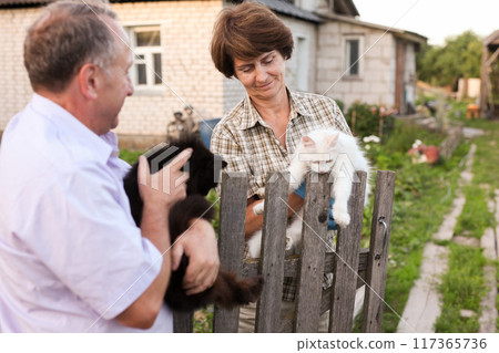 Neighbors, an elderly man and woman, with cats in their arms 117365736