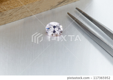 macro mineral faceted stone Morganite with tweezers on a gray background 117365952