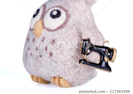 small pillow for needles in the form of an owl and a sewing machine on a white background 117365999