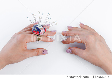 a ring with a small pillow for needles on a hand and scissors on a white background 117366003
