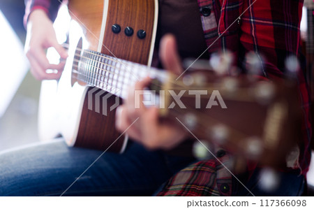 Girl tuning guitar. Focus on strings of guitar 117366098