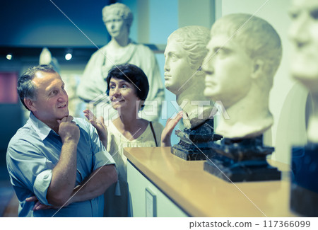 Mature couple turists examines the exhibit in museum 117366099