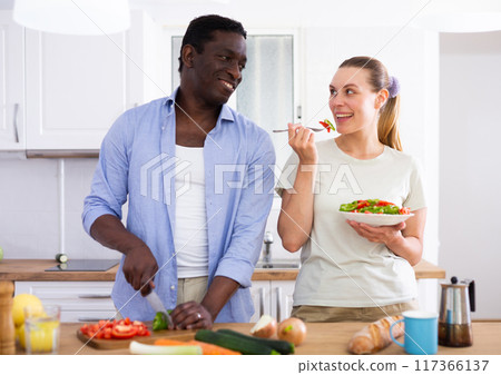 Positive couple cooking salad together at home Positive couple cooking salad together at home 117366137