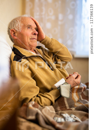 Gray haired elderly man measuring pressure with tonometer at home 117366139