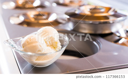 Glass dessert bowl with vanilla ice cream on the table in the display case for distribution Glass dessert bowl with vanilla ice cream on the table in the display case for distribution 117366153