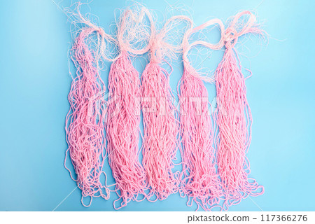 Top view of rows of pink beads on a blue background. 117366276