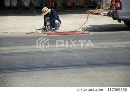 Technicians are repairing and welding a manhole cover on a road. Technicians are repairing and welding a manhole cover on a road. 117366886