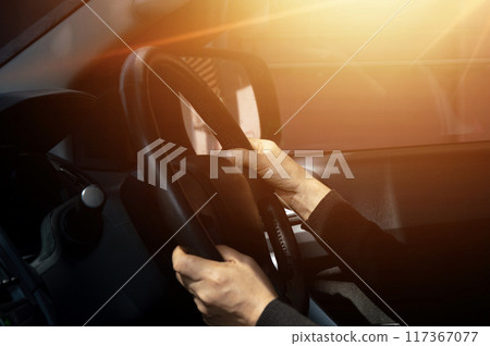 Man driving car, hand on steering wheel, looking at the road ahead,sunset. Man driving car, hand on steering wheel, looking at the road ahead,sunset. 117367077