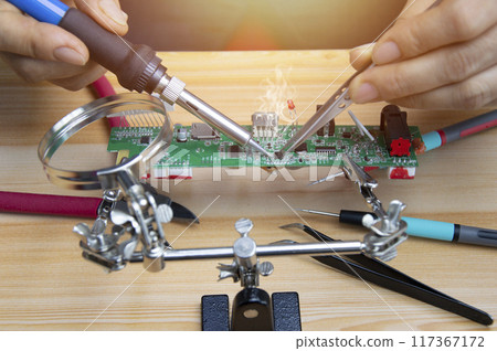 Technician is repairing motherboards and soldering equipment, repairing circuits. 117367172