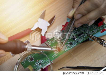 Technician is repairing motherboards and soldering equipment, repairing circuits. 117367173