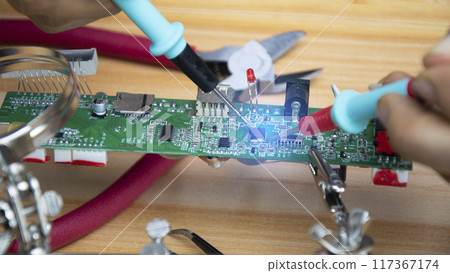 Technicians are repairing motherboards and checking electrical currents, repairing circuits. Technicians are repairing motherboards and checking electrical currents, repairing circuits. 117367174