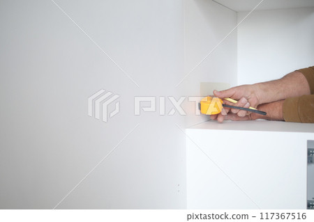 Man measuring wall with a tape measure Man measuring wall with a tape measure 117367516
