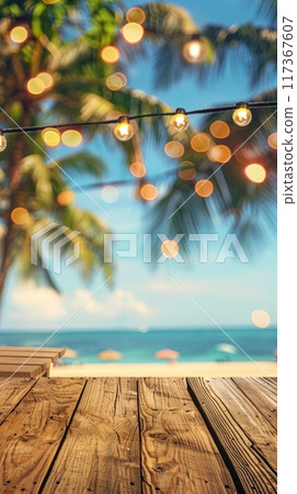 Empty wooden planks table against a blurred background with a sea coast with palm trees and glowing light bulbs in the evening 117367607