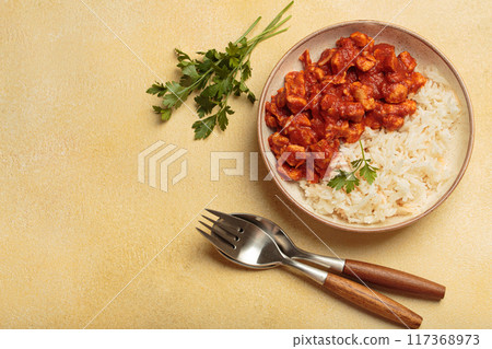 Indian chicken curry served with white rice and turmeric on yellow background top view Indian chicken curry served with white rice and turmeric on yellow background top view 117368973