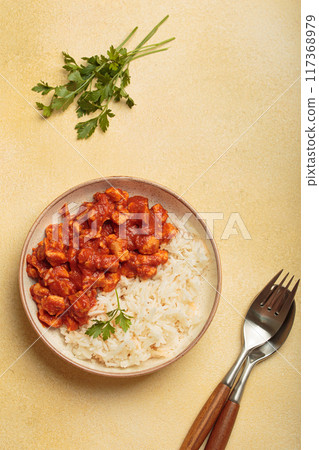 Indian chicken curry served with white rice and turmeric on yellow background top view Indian chicken curry served with white rice and turmeric on yellow background top view 117368979