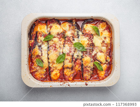 Delicious eggplant parmigiana di melanzane with tomato sauce and basil leaves top view 117368993