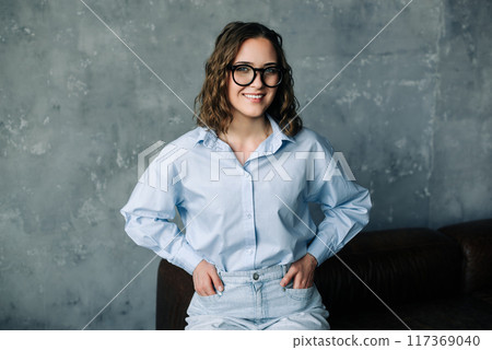 Portrait of a confident young businesswoman smiling while looking out of a window. Ideal for themes 117369040