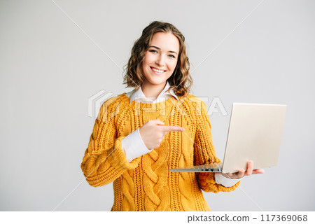 Young Woman Presenting E-Learning on Laptop. Cheerful female student pointing at a laptop screen 117369068