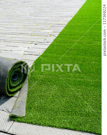 Preparing artificial grass carpet rolls for outdoor event flooring in the town square Preparing artificial grass carpet rolls for outdoor event flooring in the town square 117369224