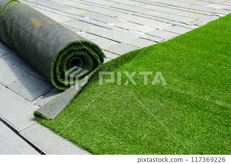 Preparing artificial grass carpet rolls for outdoor event flooring in the town square Preparing artificial grass carpet rolls for outdoor event flooring in the town square 117369226