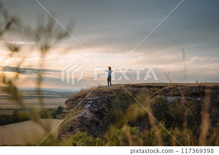 Experiencing a sense of tranquility and peace while gazing at the sunset from the edge of a cliff 117369398