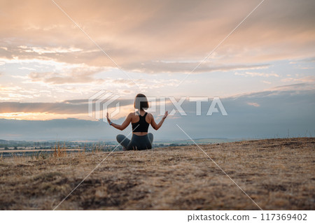 A woman meditates outside at sunset, finding relaxation and inner peace in nature A woman meditates outside at sunset, finding relaxation and inner peace in nature 117369402