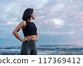 Confident Woman in Workout Gear Looking at Scenic Sky During Outdoor Fitness Session 117369412